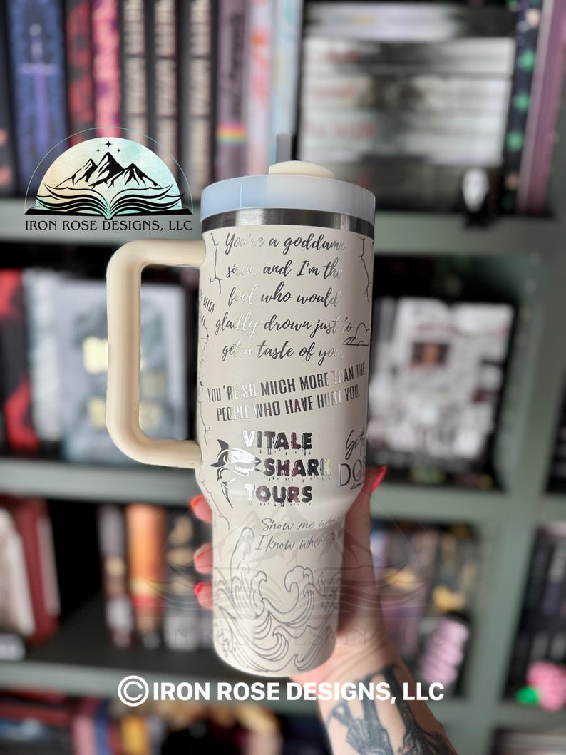 May include: White travel mug with a silver design featuring a shark and the text "You're a goddamn siren and I'm the fool who would gladly drown just to get a taste of you. You're so much more than the people who have hurt you. Vitale Shark Tours. Show me I know who's got your back."