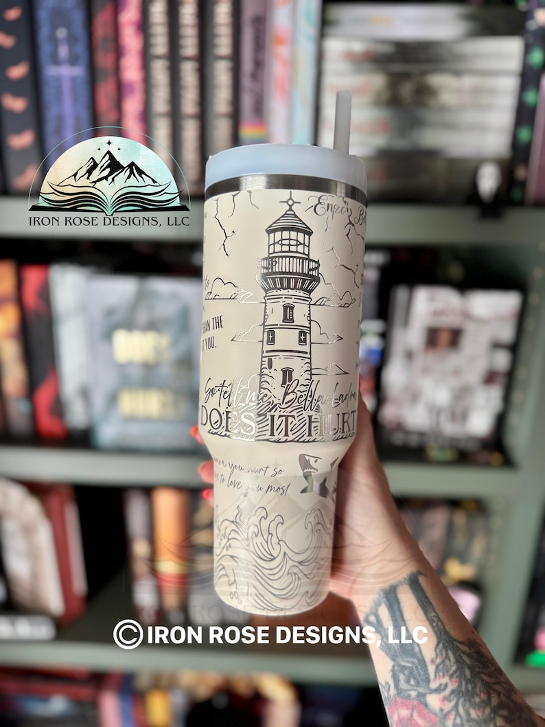 May include: A white stainless steel tumbler with a lighthouse graphic and the text "Got the Whole Bella's Gone Does It Hurt" on the side. The tumbler has a black lid and a clear straw.
