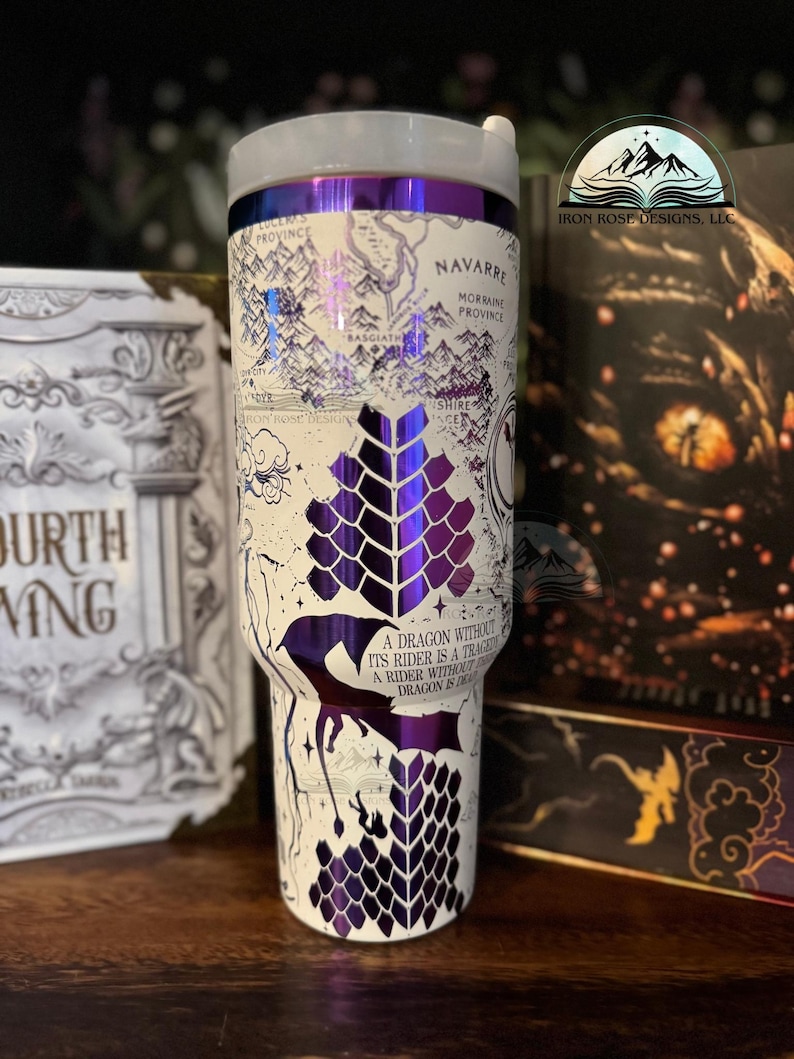 May include: A white stainless steel tumbler with a purple and white dragon design. The tumbler features a map of the fictional land of Andor from the Wheel of Time series. The text "A dragon without its rider is a tragedy. A rider without a dragon is even more so." is printed on the tumbler.