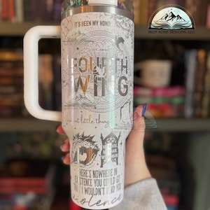 May include: A white stainless steel tumbler with a black and white graphic design featuring the text "Fourth Wing" and a quote from the book. The tumbler has a white handle and a black lid.
