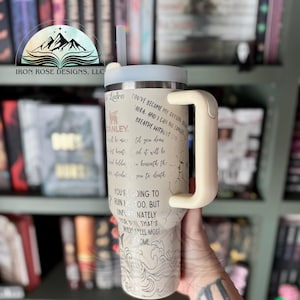 May include: A white and gray stainless steel tumbler with a black handle and a straw. The tumbler has a quote on it that reads "You've become my oxygen, Adra. And I can no longer breathe without you."