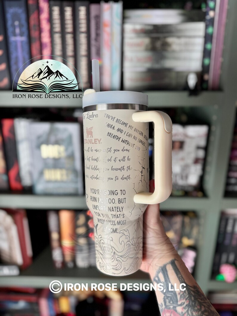 May include: A white and gray stainless steel tumbler with a black handle and a straw. The tumbler has a quote on it that reads "You've become my oxygen, Adra. And I can no longer breathe without you."