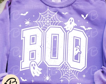 Può includere: Una felpa lilla con una grafica bianca che dice "BOO" in un font universitario. Il design include fantasmi, ragnatele, ragni e pipistrelli, perfetto per Halloween. Il testo "BARAA DIGITALDESIGN" è in basso.