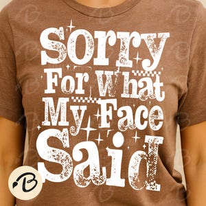 Pu&ograve; includere: T-shirt marrone con la scritta "Sorry For What My Face Said" in un carattere bianco invecchiato. Il testo &egrave; impilato e decorato con stelle. La t-shirt ha un girocollo e maniche corte.