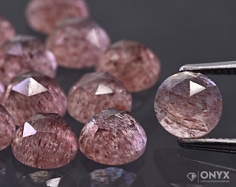 Pode incluir: Um grupo de 12 pedras preciosas de quartzo rosa facetadas de cor rosa e branca. As pedras preciosas são redondas e têm um acabamento liso e polido.