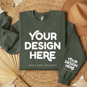 May include: A green sweatshirt with the text "YOUR DESIGN HERE" in white on the front and back. The sweatshirt is laid flat on a woven surface with a straw hat and a fan.