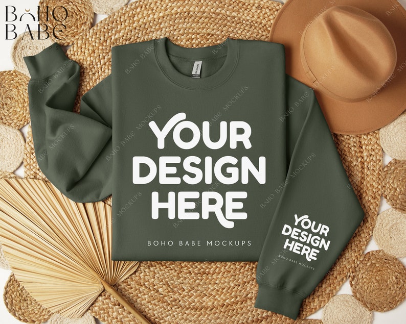 May include: A green sweatshirt with the text "YOUR DESIGN HERE" in white on the front and back. The sweatshirt is laid flat on a woven surface with a straw hat and a fan.