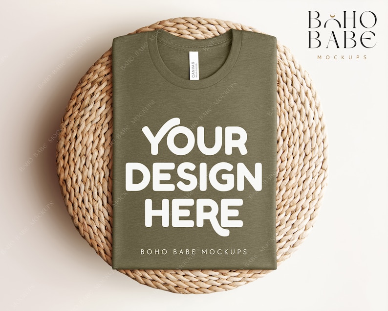 Może przedstawiać: Złożony oliwkowy t-shirt z napisem "YOUR DESIGN HERE" w kolorze białym na plecionym słomkowym dywaniku. Na koszulce nadrukowany jest napis "BOHO BABE MOCKUPS".