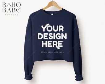 May include: A navy blue cropped sweatshirt with long sleeves. The sweatshirt has the text "YOUR DESIGN HERE" printed in white on the front.