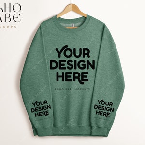 May include: A green sweatshirt with the text "YOUR DESIGN HERE" on the front and the same text on both sleeves.  BOHO BABE MOCKUPS is printed below the text on the front.
