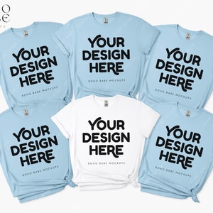 May include: Five t-shirts, four in light blue and one in white, are stacked and arranged on a white background. Each shirt has the text "YOUR DESIGN HERE" printed in black on the front.