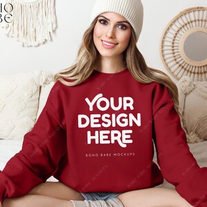 May include: A red sweatshirt with the text "YOUR DESIGN HERE" in white. The sweatshirt is being modeled by a person wearing a white beanie.