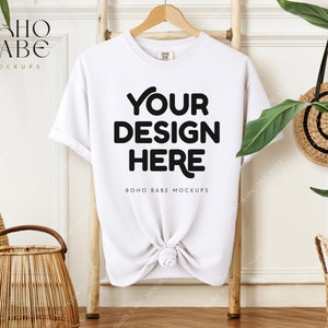 May include: White t-shirt mockup with the text "YOUR DESIGN HERE" and "BOHO BABE MOCKUPS" on a wooden ladder with a wicker basket and a green plant in the background.
