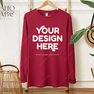May include: Red long-sleeved shirt with the text "YOUR DESIGN HERE" and "BOHO BABE MOCKUPS" printed on the front.
