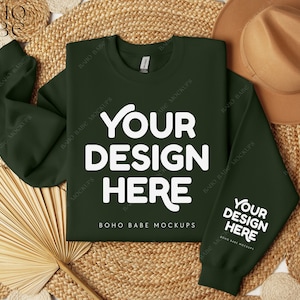 Może przedstawiać: Zielony sweter z napisem "YOUR DESIGN HERE" w kolorze białym z przodu i z tyłu. Sweter leży płasko na plecionym słomianym dywaniku z brązowym kapeluszem i wachlarzem.