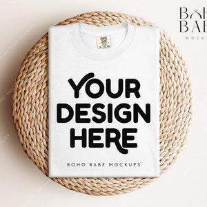 May include: White t-shirt mockup on a woven round mat. The t-shirt has the text "YOUR DESIGN HERE" printed on the front.