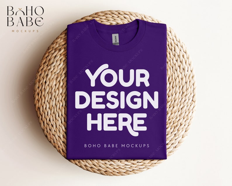 May include: Purple t-shirt mockup with the text "YOUR DESIGN HERE" on a woven straw mat.  BOHO BABE MOCKUPS is printed on the bottom of the shirt.