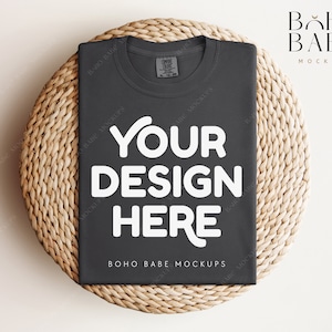 May include: A dark gray t-shirt with the text "YOUR DESIGN HERE" in white on a woven wicker surface. The text "BOHO BABE MOCKUPS" is also visible on the shirt.