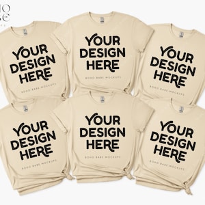 May include: Six beige t-shirts stacked on top of each other. Each shirt has the text "YOUR DESIGN HERE" printed in black on the front. The text "BOHO BABE MOCKUPS" is printed in black below the main text.