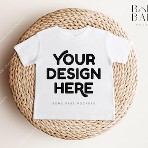 May include: White t-shirt mockup on a woven round surface. The t-shirt has the text "YOUR DESIGN HERE" and "BOHO BABE MOCKUPS" printed on it.