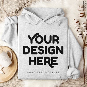 Puede incluir: Una sudadera con capucha gris con el texto "YOUR DESIGN HERE" y "BOHO BABE MOCKUPS" impreso en la parte delantera.