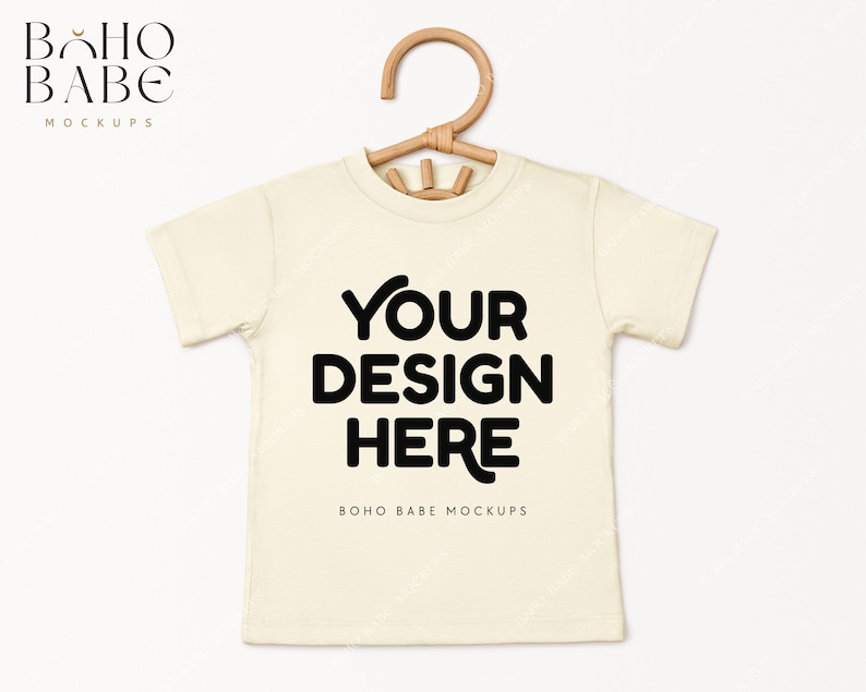 May include: A white t-shirt mockup with a wooden hanger. The text "YOUR DESIGN HERE" is printed on the front of the shirt. The text "BOHO BABE MOCKUPS" is printed below the design.