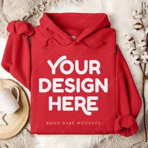 Puede incluir: Maqueta de sudadera con capucha roja con el texto "Your Design Here" sobre un fondo blanco peludo.