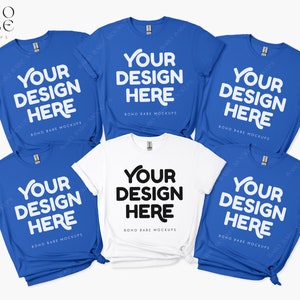 May include: Five t-shirts, four blue and one white, laid out on a white surface. Each shirt has the text "Your Design Here" printed on the front. The text is in white on the blue shirts and black on the white shirt.