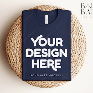 Może przedstawiać: Makieta koszulki w kolorze granatowym z napisem "YOUR DESIGN HERE" w kolorze białym na plecionym podkładce z wikliny. Na koszulce widoczny jest r&oacute;wnież napis "BOHO BABE MOCKUPS".