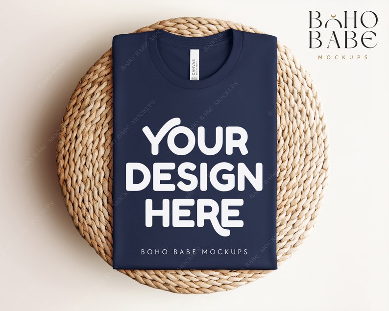 Może przedstawiać: Makieta koszulki w kolorze granatowym z napisem "YOUR DESIGN HERE" w kolorze białym na plecionym podkładce z wikliny. Na koszulce widoczny jest r&oacute;wnież napis "BOHO BABE MOCKUPS".