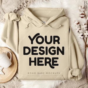 Puede incluir: Una sudadera con capucha beige con capucha y cord&oacute;n. La sudadera tiene el texto "YOUR DESIGN HERE" y "BOHO BABE MOCKUPS" impreso en la parte delantera.