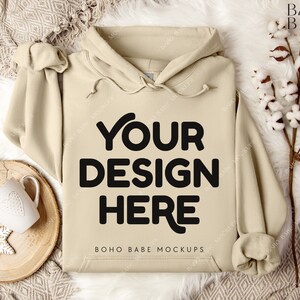 Puede incluir: Una sudadera con capucha beige con capucha y cord&oacute;n. La sudadera tiene el texto "YOUR DESIGN HERE" y "BOHO BABE MOCKUPS" impreso en la parte delantera.