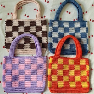 May include: Four crocheted tote bags with checkered patterns in different colors. The bags are brown and white, blue and white, purple and pink, and orange and yellow.