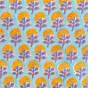 Può includere: Un motivo ripetuto di fiori gialli con accenti rossi e steli e foglie viola su sfondo azzurro. Il design floreale è uniformemente distribuito sul tessuto, creando un tessuto visivamente accattivante.