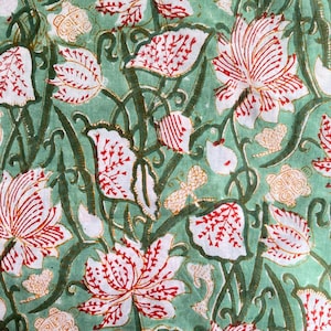 May include: A fabric featuring a repeating floral design. Large white flowers with red striped details are set amongst white leaves with red accents. The background is a light green colour, with dark green stems and vines.