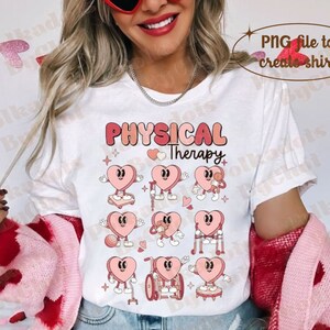 May include: White t-shirt featuring the words "PHYSICAL Therapy" in pink and peach lettering, with heart-shaped characters demonstrating physical therapy exercises. The design includes hearts with arms and legs, some using crutches or wheelchairs.
