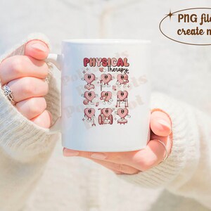 May include: White ceramic mug featuring the words "Physical Therapy" in a retro font, along with cartoon heart characters. The hearts are depicted in various physical therapy scenarios. The mug is held by a person wearing a cream-colored sweater.