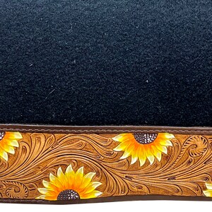 May include: Black saddle pad with a brown leather border featuring a sunflower design.