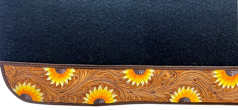 May include: Black saddle pad with a brown leather border featuring a sunflower design.