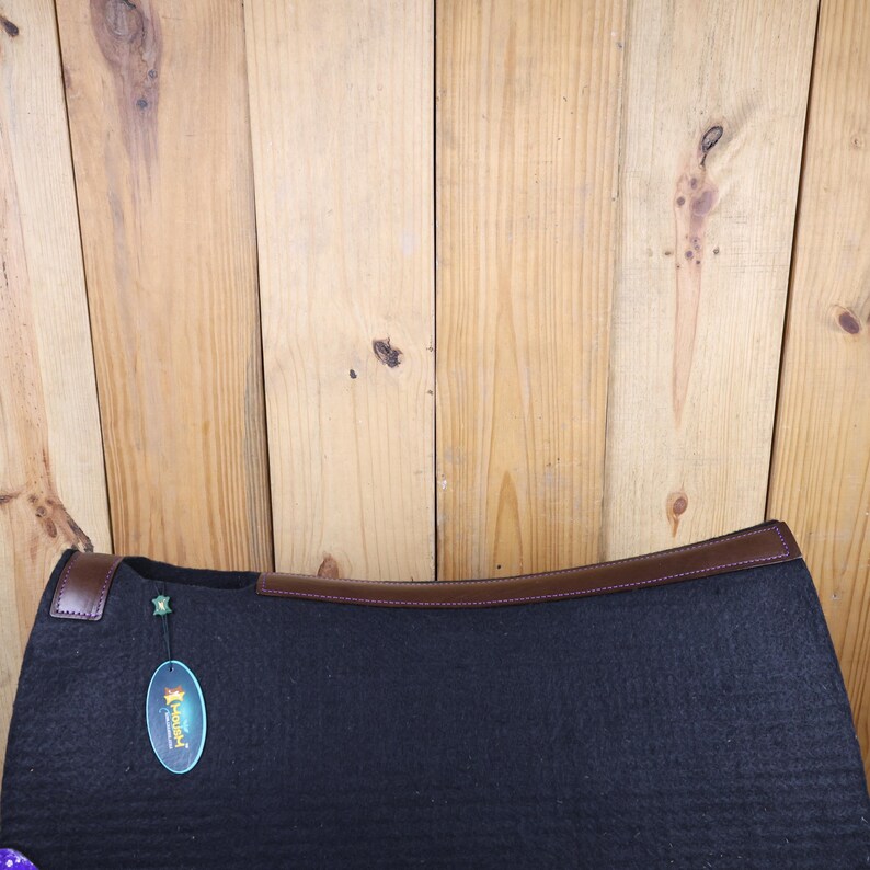 May include: Black saddle pad with brown leather trim and a green and yellow label that says "Horseware".