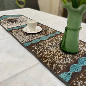 Chemin de table artisanal en cuir de vachette : empiècements en cuir turquoise, marron et blanc