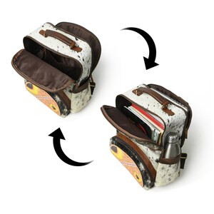 May include: A white and brown cowhide backpack with sunflower accents. The backpack has a brown leather handle and a zip closure. The backpack is shown open with a brown lining and a water bottle inside.