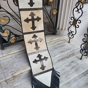 May include: A white and black fabric banner with a fringe border. The banner features four black crosses with a leopard print design. The banner is hanging on a set of stairs.