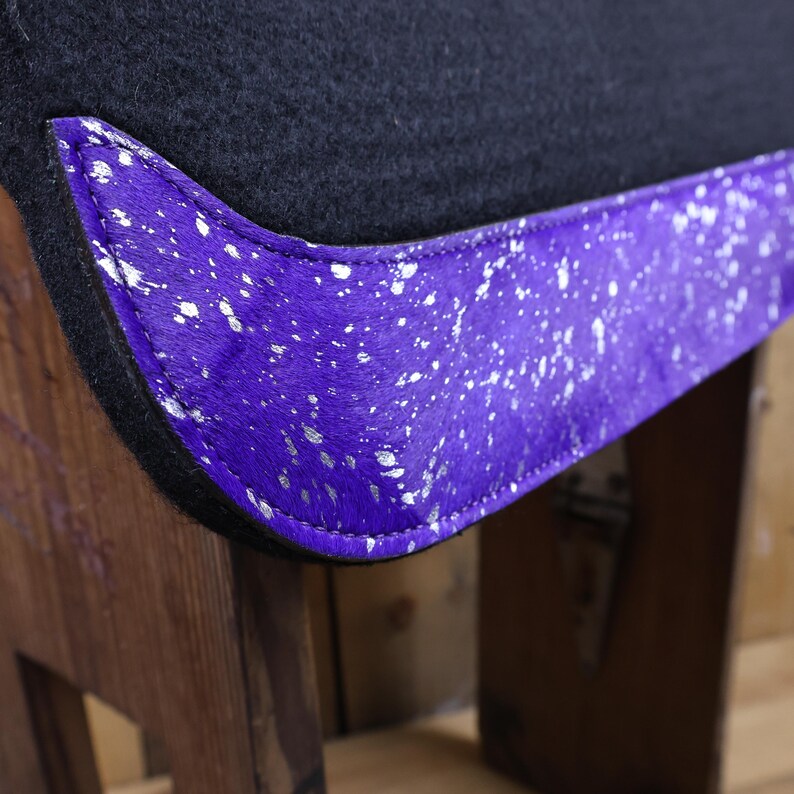 May include: Purple saddle pad with a silver and white speckled trim. The pad is made of a soft, plush material and is designed to provide comfort and support for your horse.
