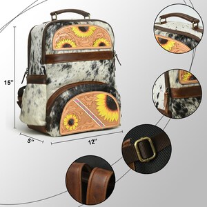 May include: A white and brown cowhide backpack with sunflower and floral embroidery. The backpack has a top handle, adjustable straps, and a zipped front pocket. It measures 15 inches tall, 12 inches wide, and 5 inches deep.