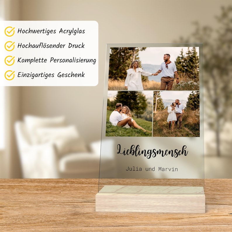 May include: A clear acrylic photo display with three images of a couple. The display has a wooden base and features the German word "Lieblingsmensch" and the names "Julia und Marvin". The top left corner has text in German.