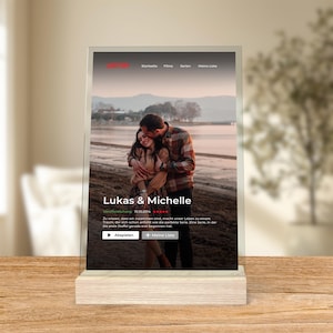 May include: A digital screen displaying a couple on a beach with the title "Lukas & Michelle" and the text "10.10.2014". The screen also has buttons for "Play" and "Add to My List".