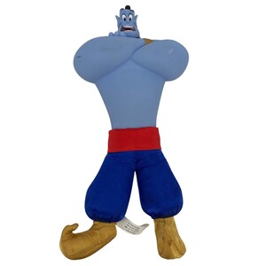 Op de afbeelding: Een pluche speelgoed van de Genie uit Disney's Aladdin. De Genie is blauw met een rode tailleband en een blauwe broek. Zijn schoenen zijn bruin. Het speelgoed heeft een glimlachende uitdrukking en staat met één been naar voren.