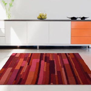 May include: A red, orange, and pink striped area rug with a modern geometric design.