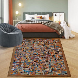 May include: A colorful, geometric patterned rug with a brown border. The rug is made of woven fabric and has a variety of colors, including orange, blue, green, and yellow.
